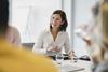 A business woman laughs with colleagues in a meeting